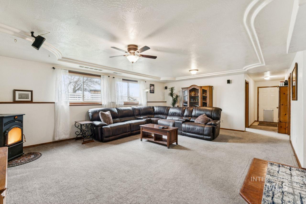 710 Keogh Lane Caldwell, ID 83607 - Photo 33 of 50 Living room with a wood stove, carpet, a textured ceiling, ceiling fan, and a raised ceiling