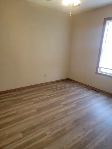 a view of a room with wooden floor and a ceiling fan