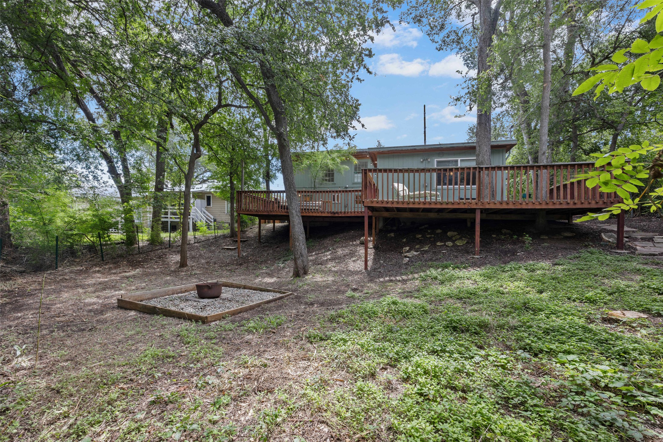 3302 Cherrywood Road Austin, TX 78722 - Photo 22 of 26 A spacious raised deck overlooks a fenced-in backyard with mature trees and a fire pit area.