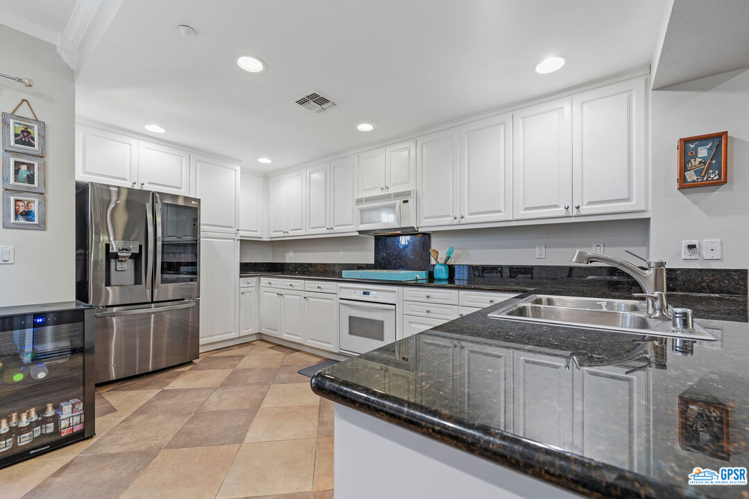 22 Paseo Rosa San Clemente, CA 92673 - Photo 11 of 24 a kitchen with granite countertop a refrigerator sink and white cabinets