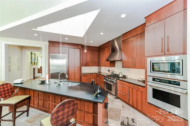 a kitchen with stainless steel appliances a stove a sink a microwave a refrigerator and cabinets