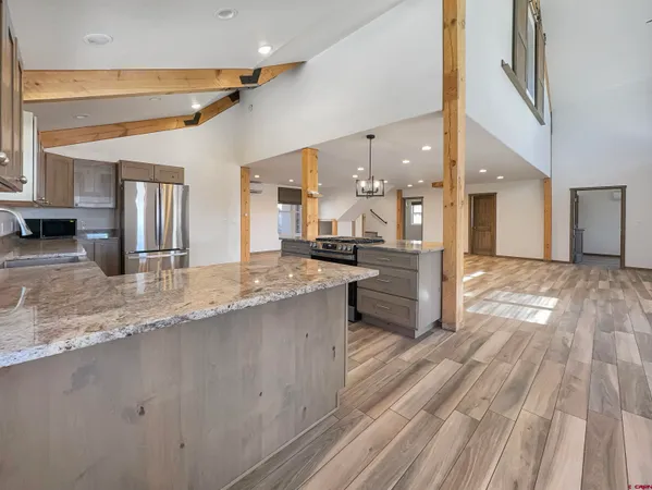 a large kitchen with stainless steel appliances kitchen island a large counter top and a wooden floors