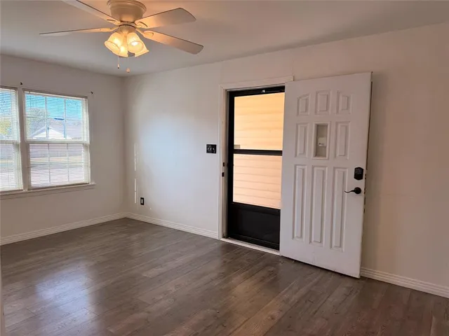 an empty room with wooden floor chandelier and windows
