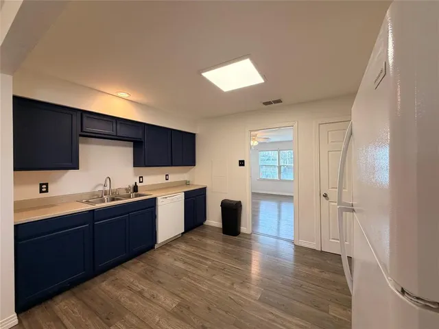 a large kitchen with lot of cabinets and wooden floor