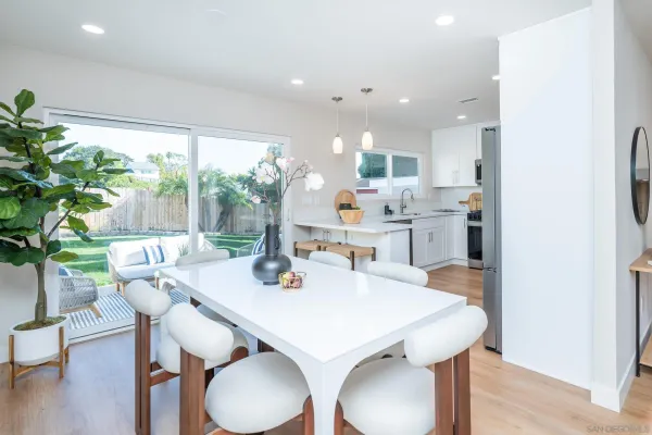a kitchen with white cabinets stainless steel appliances and dining table