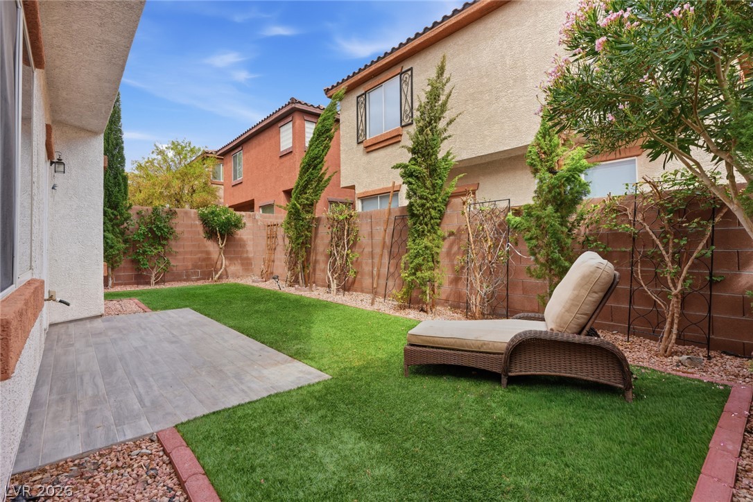 8932 Caledon Ridge Court Las Vegas, NV 89149 - Photo 9 of 39 A private walled backyard features a small tiled patio area and a manicured green lawn.
