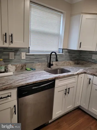 a kitchen with granite countertop a sink cabinets and wooden floor