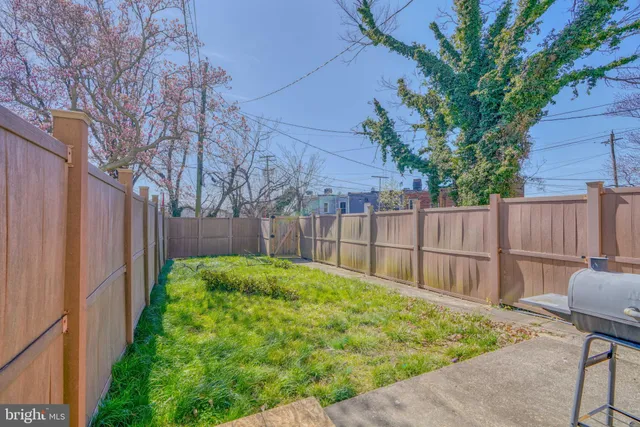 a view of a backyard with table and chairs with wooden fence and large trees