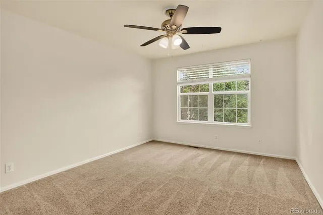 an empty room with a window and a fan