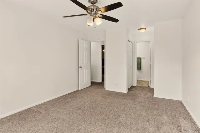 an empty room with closet and a ceiling fan