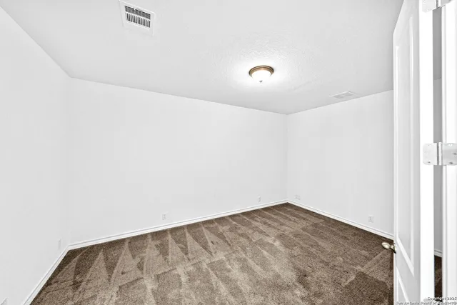 a view of a white house with a yard plants and large tree