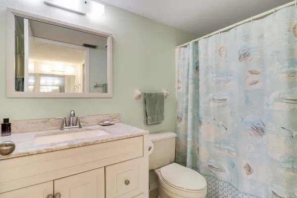 a bathroom with a granite countertop sink a toilet and a mirror