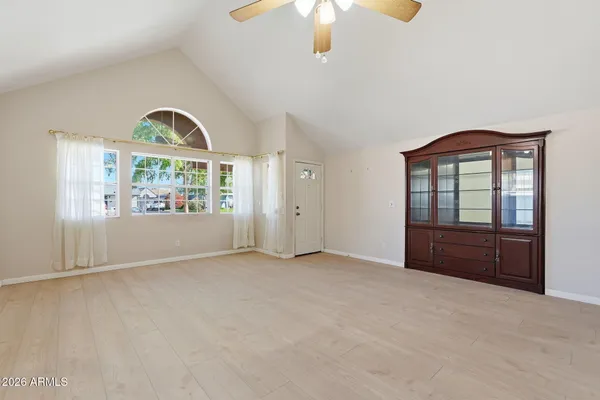an empty room with chandelier fan and windows