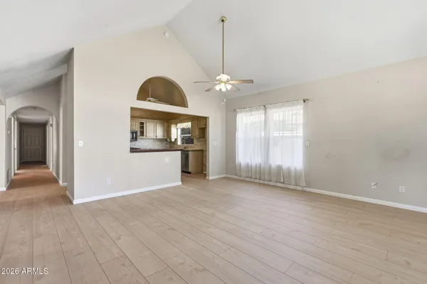 an empty room with wooden floor fan and windows