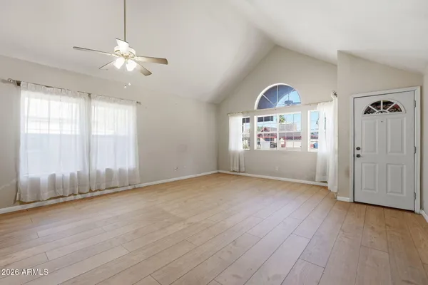an empty room with chandelier fan and windows