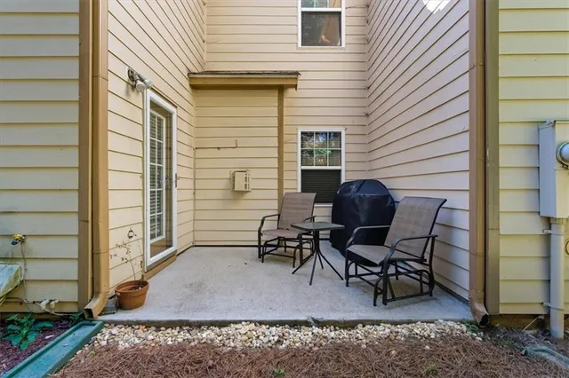 a patio with table and chairs and potted plants