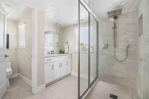 a bathroom with a granite countertop sink a mirror a toilet and shower