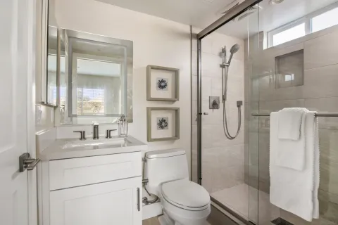 a bathroom with a shower sink vanity mirror and toilet