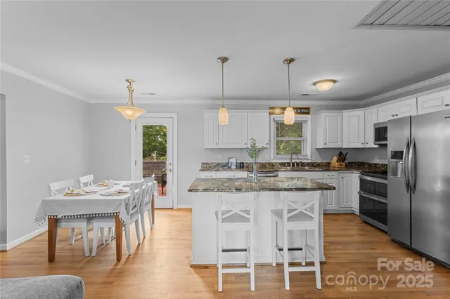 a kitchen with granite countertop kitchen island stainless steel appliances a dining table and chairs