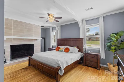 a bedroom with a bed a fireplace and wooden floor