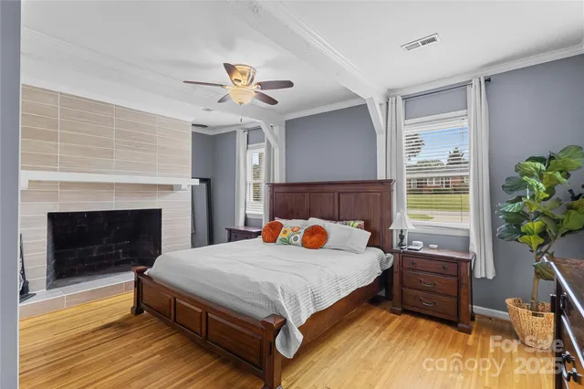 a bedroom with a bed a fireplace and wooden floor
