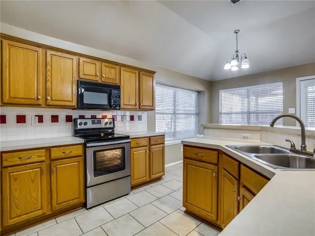 a kitchen with stainless steel appliances granite countertop a stove sink microwave and window