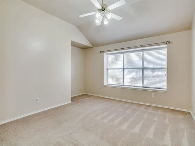 an empty room with chandelier fan and windows