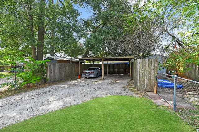 a view of a backyard with table and chairs plants and large tree