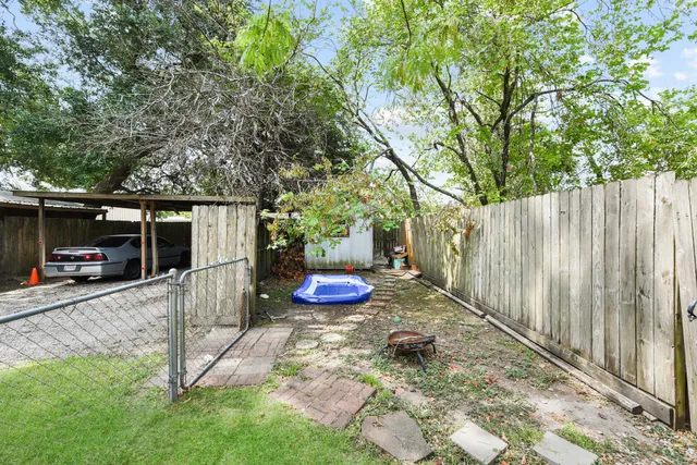 a view of a backyard with table and chairs potted plants and large tree