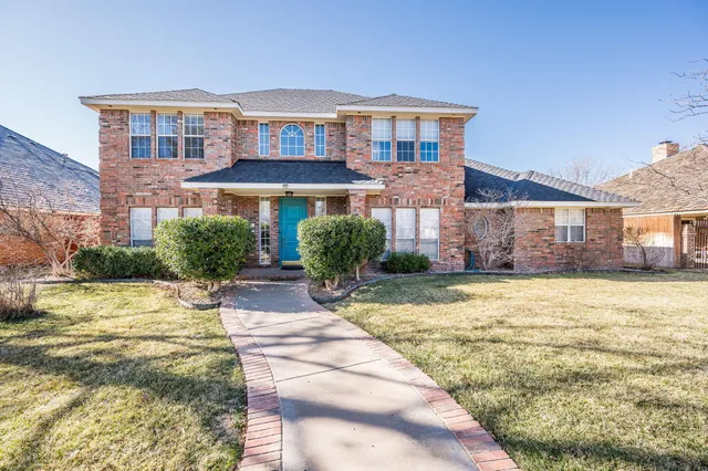 a front view of a house with a yard and potted plants