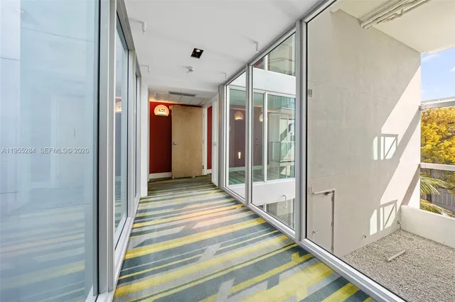 a view of a hallway with wooden floor and windows