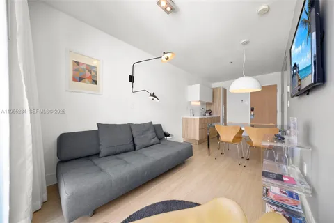 a living room with furniture kitchen view and a chandelier
