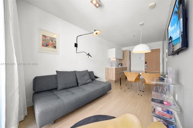 a living room with furniture kitchen view and a chandelier