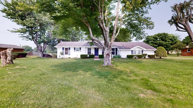 a front view of a house with a yard and trees