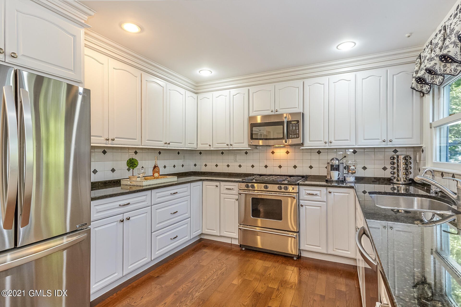 27 Perryridge Road Greenwich, CT 06830 - Photo 5 of 24 a kitchen with stainless steel appliances granite countertop a stove top oven a refrigerator a sink and dishwasher with wooden floor