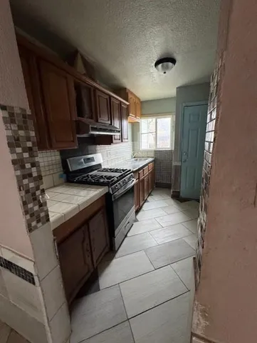 a kitchen with stainless steel appliances granite countertop a stove a sink and a microwave