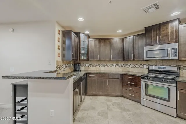 a kitchen with stainless steel appliances granite countertop a stove top oven a sink and dishwasher