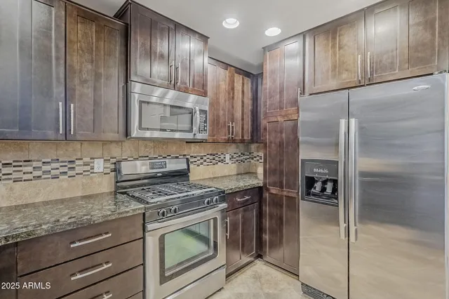 a kitchen with granite countertop wooden cabinets and stainless steel appliances