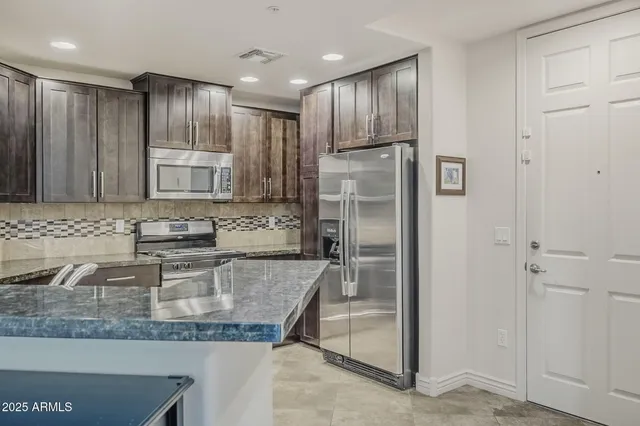 a kitchen with stainless steel appliances granite countertop a refrigerator and a sink