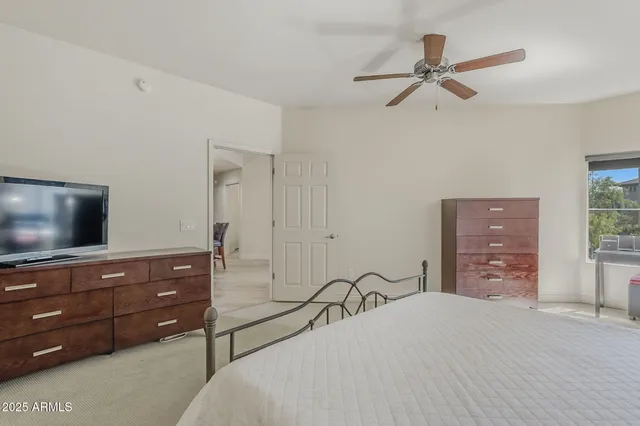 a bedroom with a bed a dresser and a flat screen tv