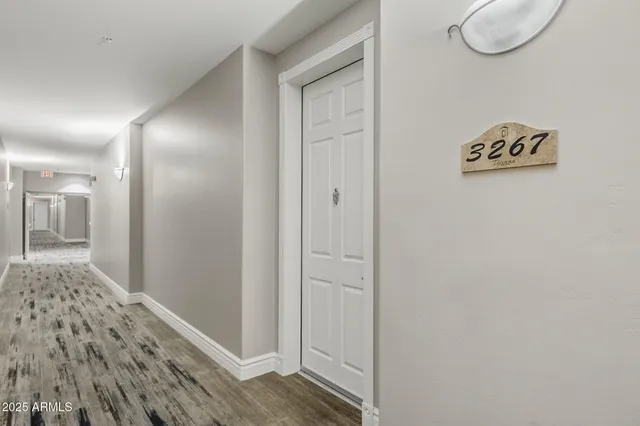 a view of a hallway with wooden floor and a bathroom
