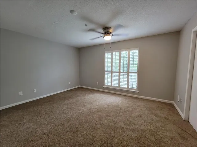 an empty room with a ceiling fan and windows