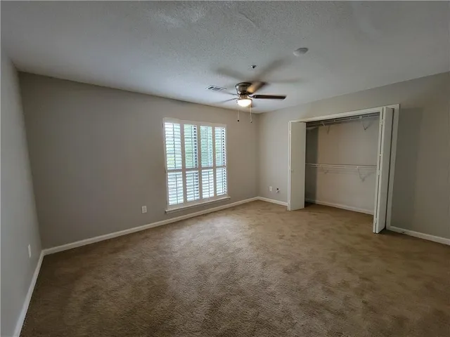 an empty room with chandelier fan and windows
