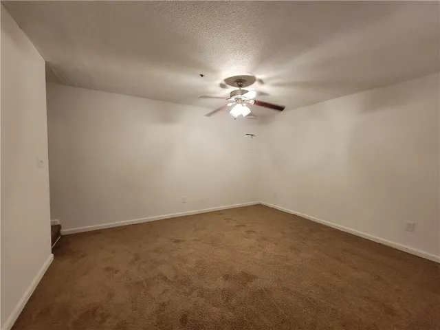 an empty room with a chandelier fan and windows