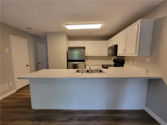 a kitchen with kitchen island a sink a stove a microwave and wooden floors