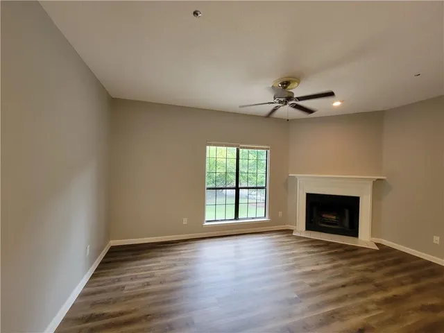 an empty room with wooden floor fireplace and a window