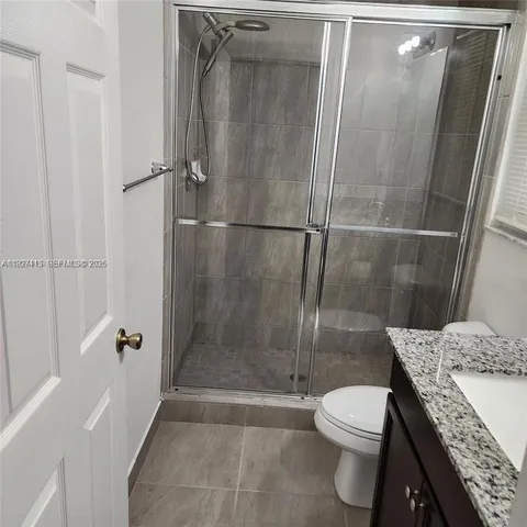a bathroom with a granite countertop sink toilet and shower