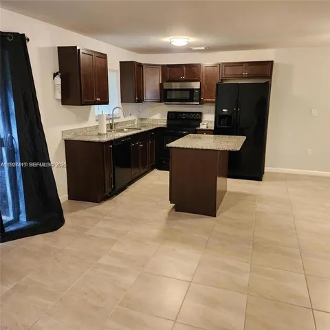 a kitchen with stainless steel appliances a sink a stove a microwave a sink a counter top space and cabinets