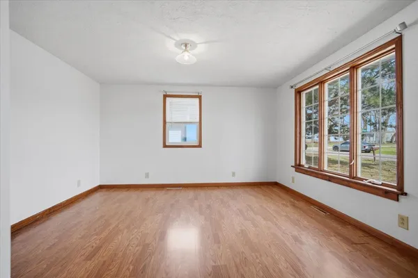 a view of an empty room with a window and wooden floor