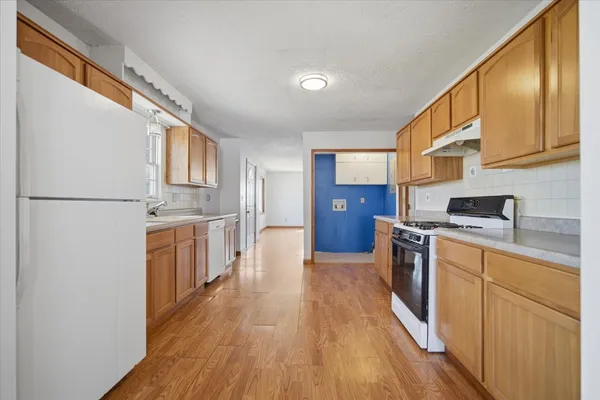 a view of an empty room with wooden floor and a bathroom
